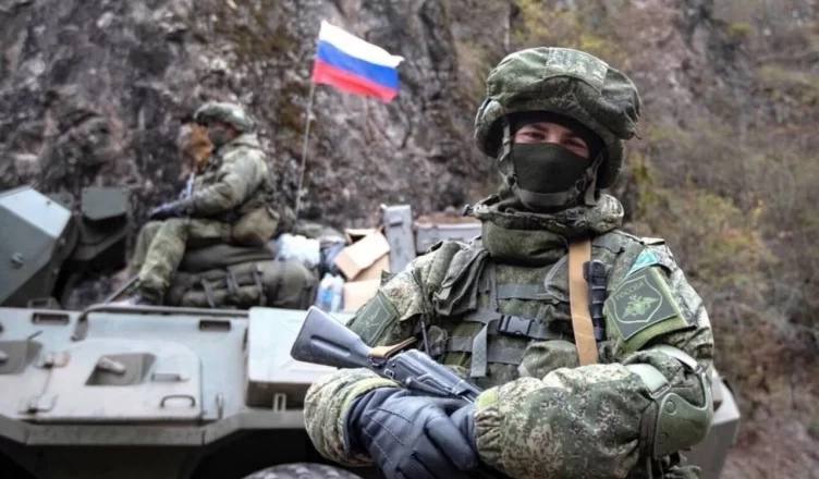 Военнослужащий у бронемашины, на заднем плане флаг России